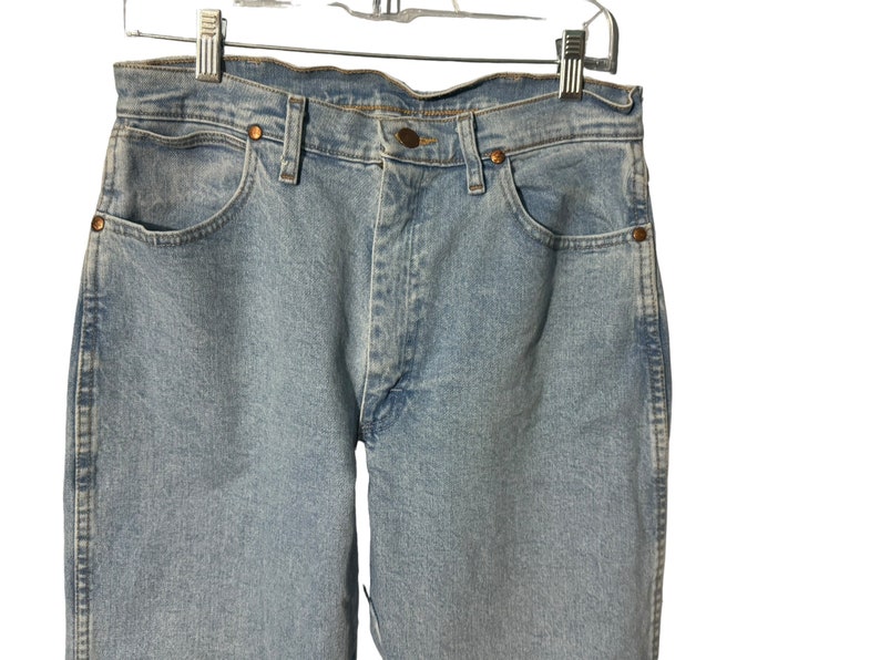 May include: Light blue denim jeans with a classic five-pocket style. The jeans have a straight leg and a button fly.