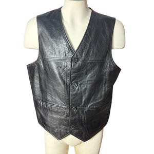 Peut inclure: Un gilet en cuir noir avec un devant à boutons et un col en V. Le gilet a deux poches sur le devant.