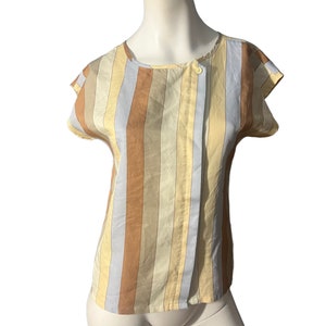 May include: A striped short-sleeved blouse with a button closure at the neck. The blouse is made of a light-weight fabric and has a relaxed fit. The colors are a mix of light blue, beige, and brown.