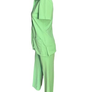 May include: A light green two-piece suit. The short-sleeved collared shirt has two front pockets and buttons down the front. The matching pants are wide-legged. The suit is displayed on a mannequin.