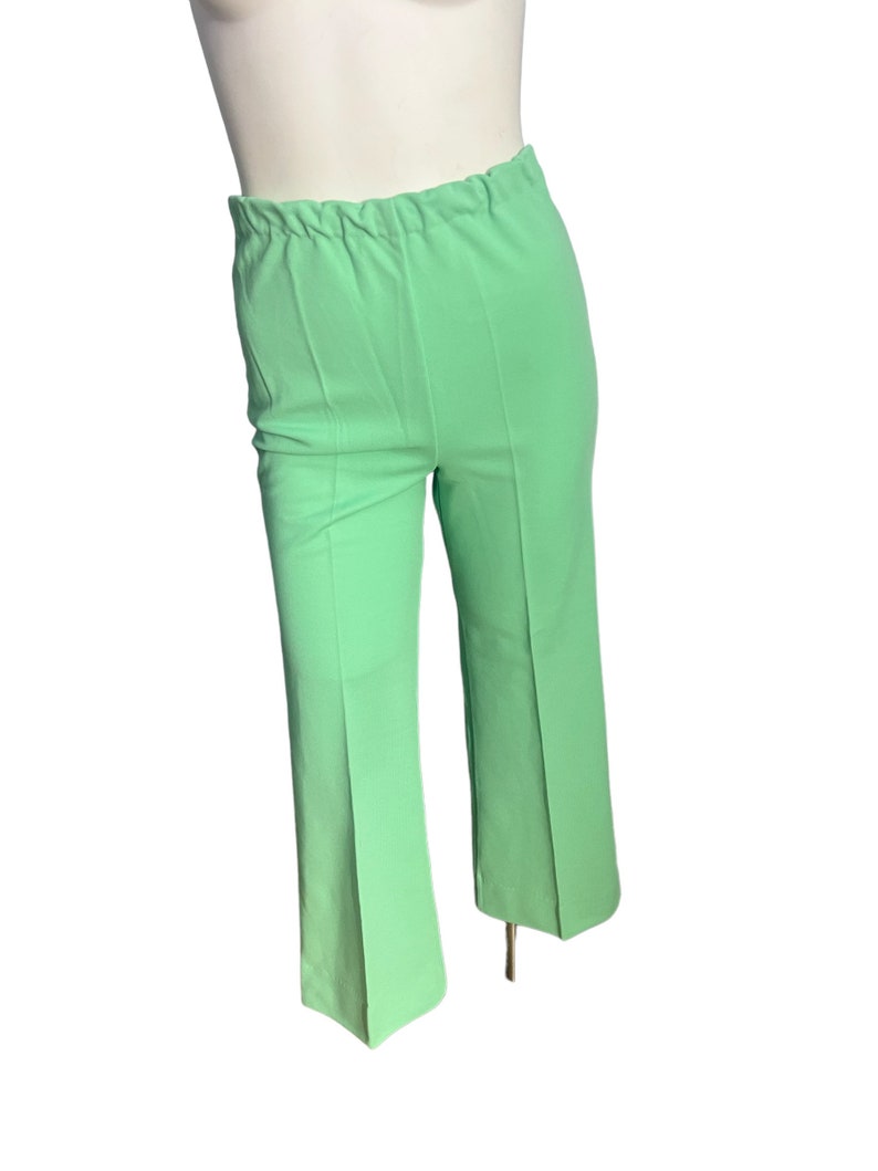 May include: Light green pants with an elastic waistband and a slight flare at the hem. The pants are a solid color and appear to be made of a lightweight fabric. The pants are displayed on a mannequin.