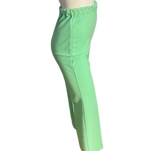 May include: Light green pants with an elastic waistband. The pants are a solid color and have a slight flare at the bottom. The fabric appears to be a lightweight material.