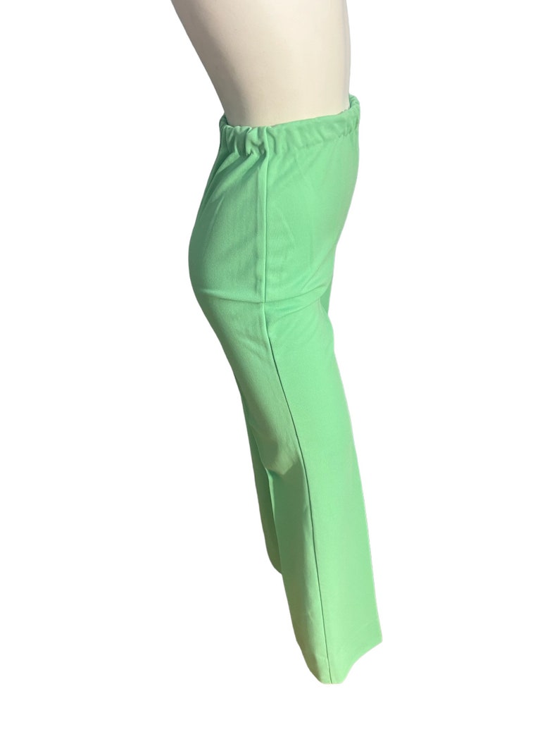 May include: Light green pants with an elastic waistband. The pants are a solid color and have a slight flare at the bottom. The fabric appears to be a lightweight material.