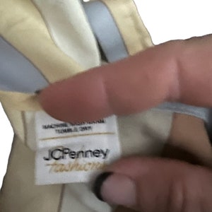 May include: A white tag with the text "JCPenney  Taffeta" in black lettering. The tag is attached to a yellow and blue striped fabric.