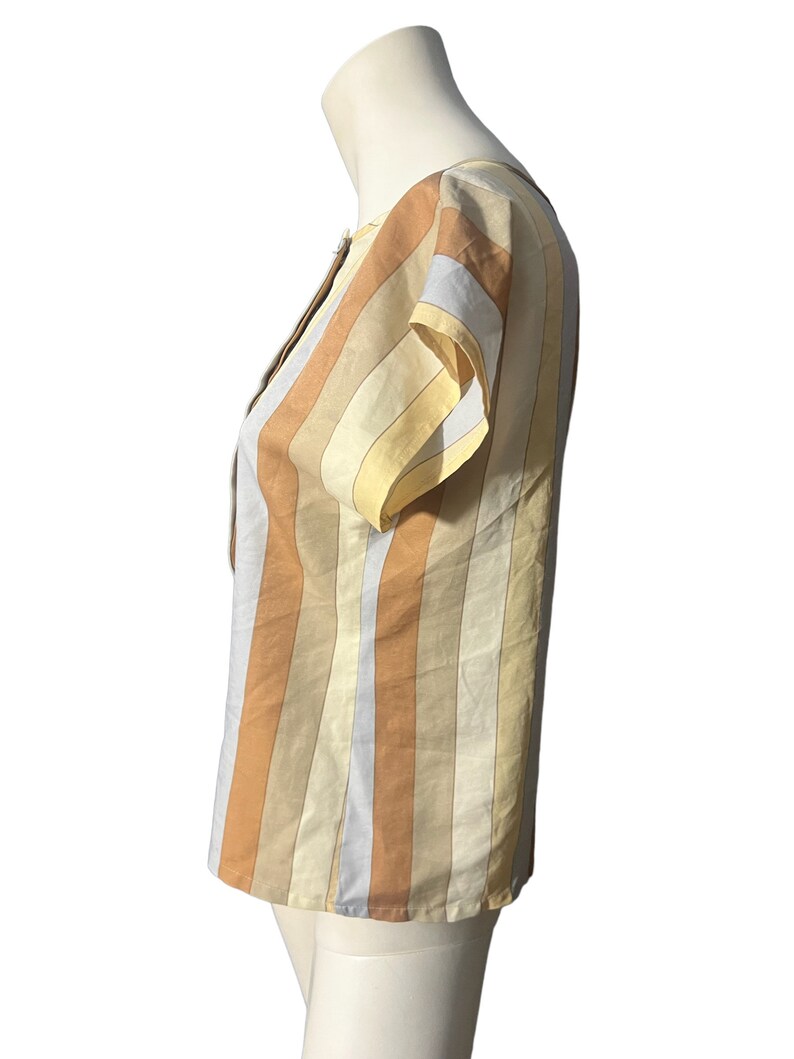 May include: A striped short-sleeved blouse with a scoop neck. The stripes are in shades of yellow, orange, and brown.