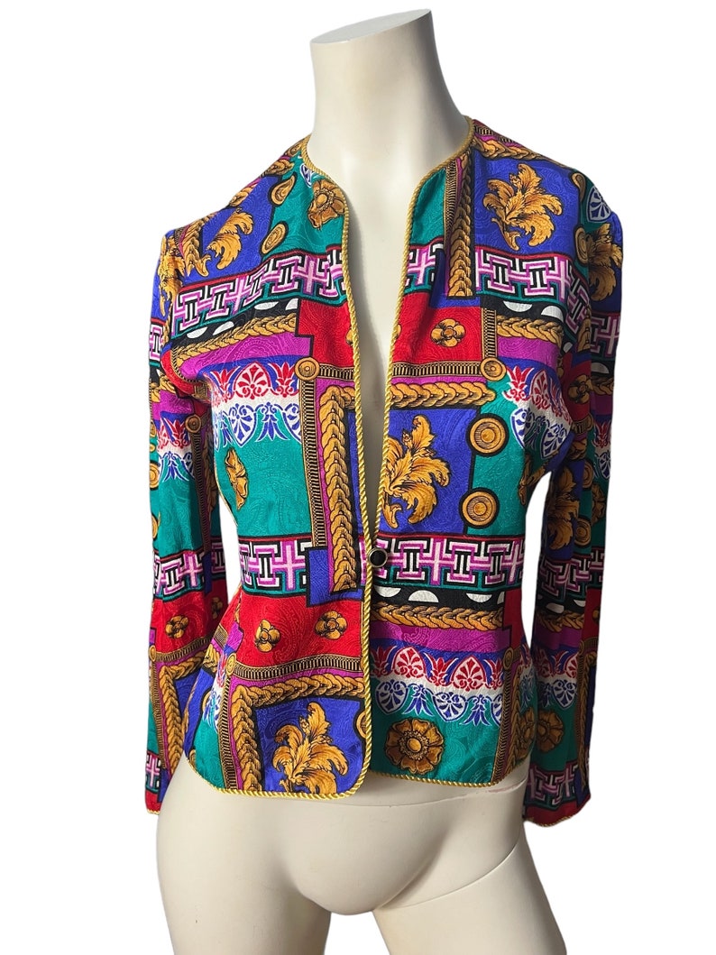 May include: A colourful patterned blazer with a gold trim. The blazer has a geometric design with a mix of red, blue, green, pink, and gold.