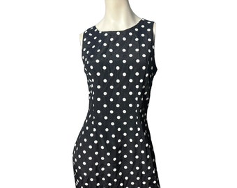 May include: A sleeveless black dress with white polka dots. The dress has a scoop neckline and a fitted bodice.