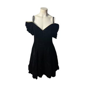 May include: A black velvet dress with off-the-shoulder sleeves and a sweetheart neckline. The dress features a fitted bodice and a flared skirt, displayed on a mannequin. The neckline and sleeve edges are trimmed with gold. The dress is a vintage style.