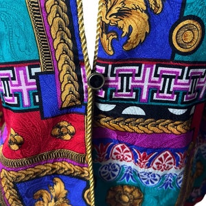 May include: Close-up of a colourful fabric with a gold trim. The fabric features a variety of geometric and floral patterns in shades of blue, red, green, yellow, and pink.