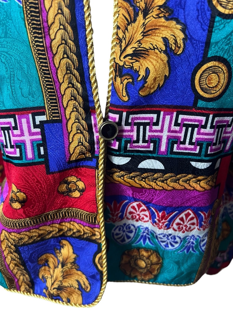 May include: Close-up of a colourful fabric with a gold trim. The fabric features a variety of geometric and floral patterns in shades of blue, red, green, yellow, and pink.