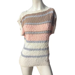 Può includere: Un maglione a righe a maniche corte nei colori crema, rosa, marrone e grigio. Il maglione ha un aspetto strutturato e lavorato a maglia, esposto su un manichino. Le strisce orizzontali sono uniformemente distanziate.