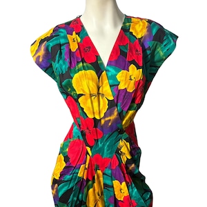 May include: A vibrant wrap dress with a colorful floral print featuring yellow, red, green, and purple flowers on a black background.