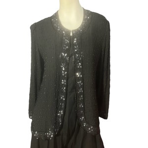 May include: A black beaded jacket with a long sleeve and a decorative beaded trim. The jacket is made of a soft, flowing fabric.