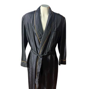 May include: A black robe with gold trim and a matching belt. The robe is displayed on a mannequin and has long sleeves. The trim is visible along the lapels, cuffs, and belt. The robe appears to be made of a silky material.