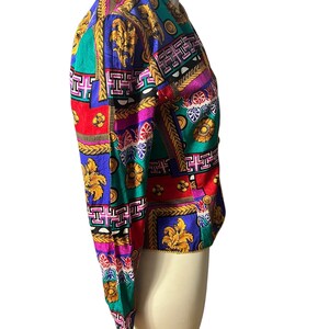 May include: A colourful, patterned jacket with a geometric design featuring gold accents. The jacket has long sleeves and a cropped length.