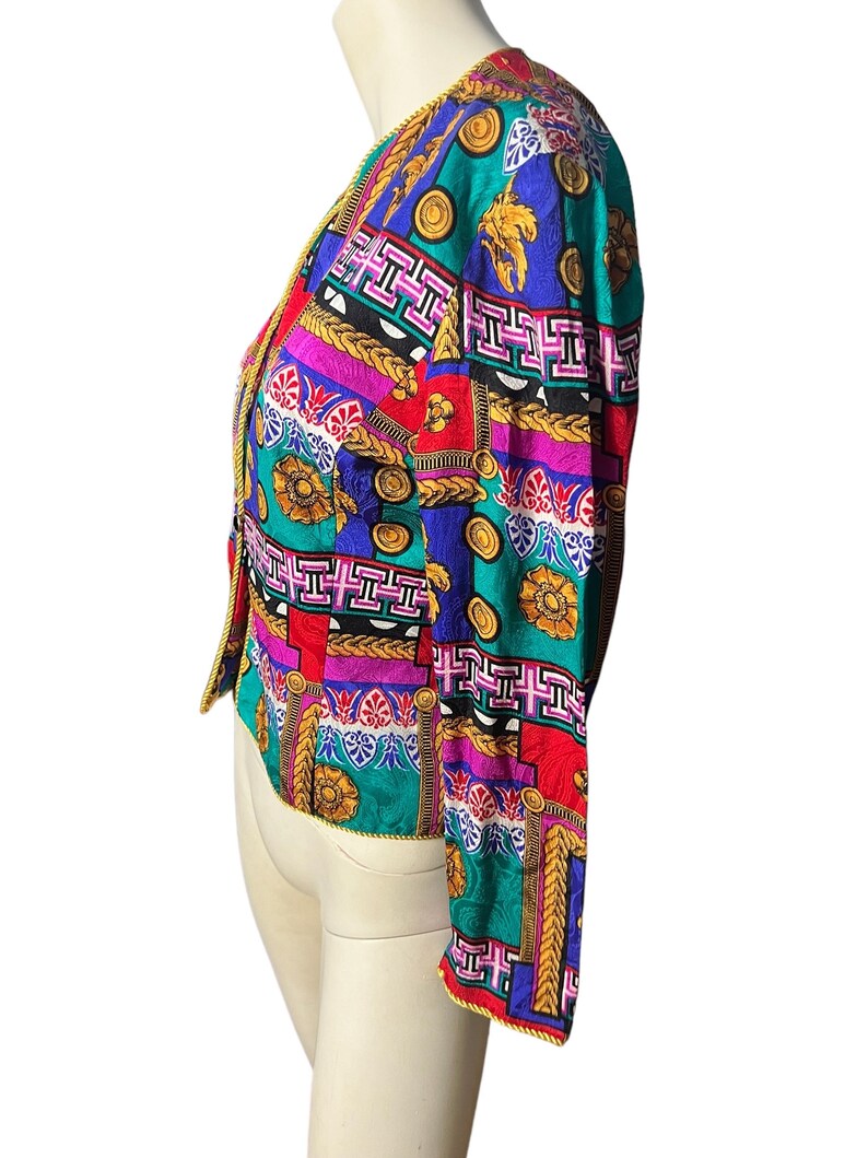 May include: A colourful, patterned jacket with a gold trim. The jacket features a variety of geometric and floral designs in shades of red, blue, green, pink, and yellow.