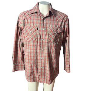 Op de afbeelding: Een overhemd met lange mouwen en knopen in een rood, groen en bruin geruit patroon. De shirt heeft twee borstzakken met knoopsluitingen en een klassieke kraag. De shirt wordt op een mannequin getoond.