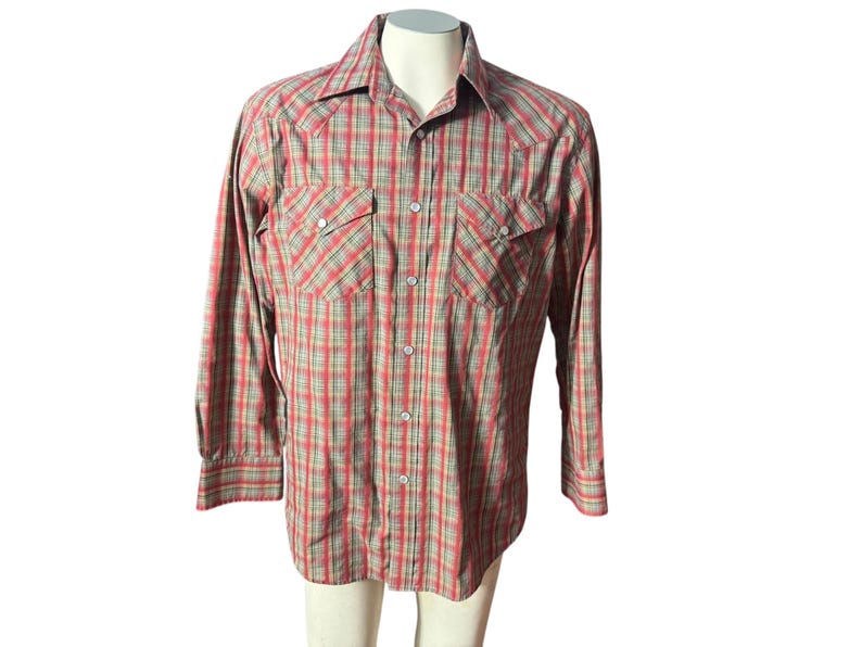 Op de afbeelding: Een overhemd met lange mouwen en knopen in een rood, groen en bruin geruit patroon. De shirt heeft twee borstzakken met knoopsluitingen en een klassieke kraag. De shirt wordt op een mannequin getoond.