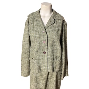 Puede incluir: Un traje vintage de tweed verde oliva, que consta de una chaqueta con cuello con tres botones y dos bolsillos delanteros, y una falda a juego. El traje se exhibe en un maniquí sobre un fondo blanco.
