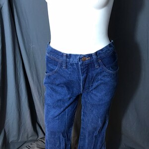 May include: Dark blue denim jeans with a classic five-pocket design. The jeans have a button and zipper closure, and a straight leg fit. The jeans are displayed on a mannequin.
