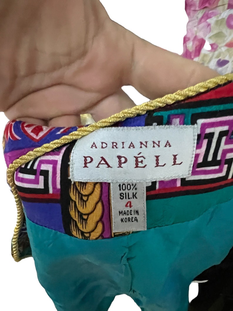 May include: A turquoise, purple, red and black silk dress with a gold rope trim. The dress has a label that reads "Adrianna Papell" and "100% Silk" with a size 4 and "Made in Korea".