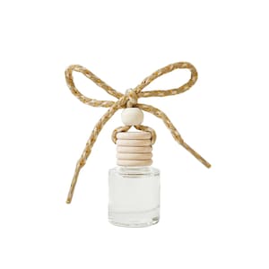 May include: Clear glass bottle with a wooden cap and a decorative bow made of gold-threaded rope. The bow is tied at the top, with a small wooden bead. The bottle is designed for fragrance or essential oils.
