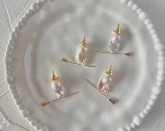May include: Four quirky pearl witch charms, each featuring a gold-coloured witch's hat and a broomstick, presented on a white, scalloped plate. The pearls have an irregular form, and the broomsticks are slender. Ideal for jewellery or craft projects.