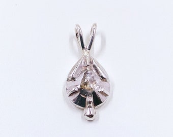 May include: A silver pendant with a teardrop-shaped design and a small clear stone in the center.