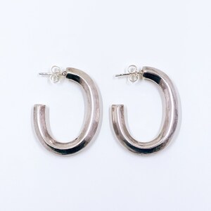 May include: A pair of silver hoop earrings with a thick, rounded design.