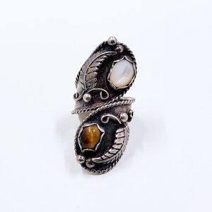 May include: A silver ring with a white and brown stone set in a leaf design.