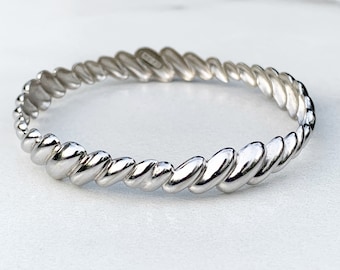 May include: A silver bangle bracelet with a twisted rope design.