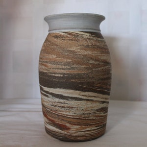 May include: A brown and white ceramic vase with a white rim. The vase has a swirling pattern of brown, white, and orange.