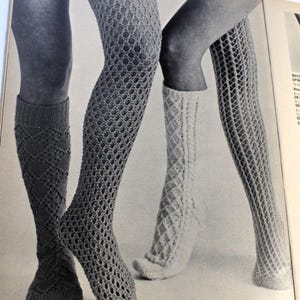 May include: Three pairs of knitted knee-high socks in different patterns. The socks are shown on a pair of legs. The socks are white, gray, and black.