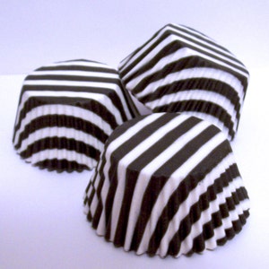 May include: Three black and white striped cupcake liners. The liners are made of paper and have a fluted design.