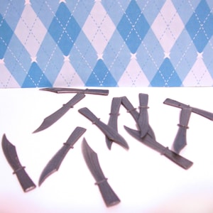 May include: A collection of ten gray plastic knives arranged in a random pattern on a white surface.
