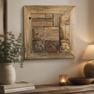 Könnte beinhalten: Quadratische Wandkunst aus Holz mit Mosaikdesign. Das Kunstwerk besteht aus unterschiedlich großen Holzblöcken, die in einem quadratischen Rahmen angeordnet sind. Das Holz hat eine natürliche, hellbraune Farbe und sichtbare Maserung.