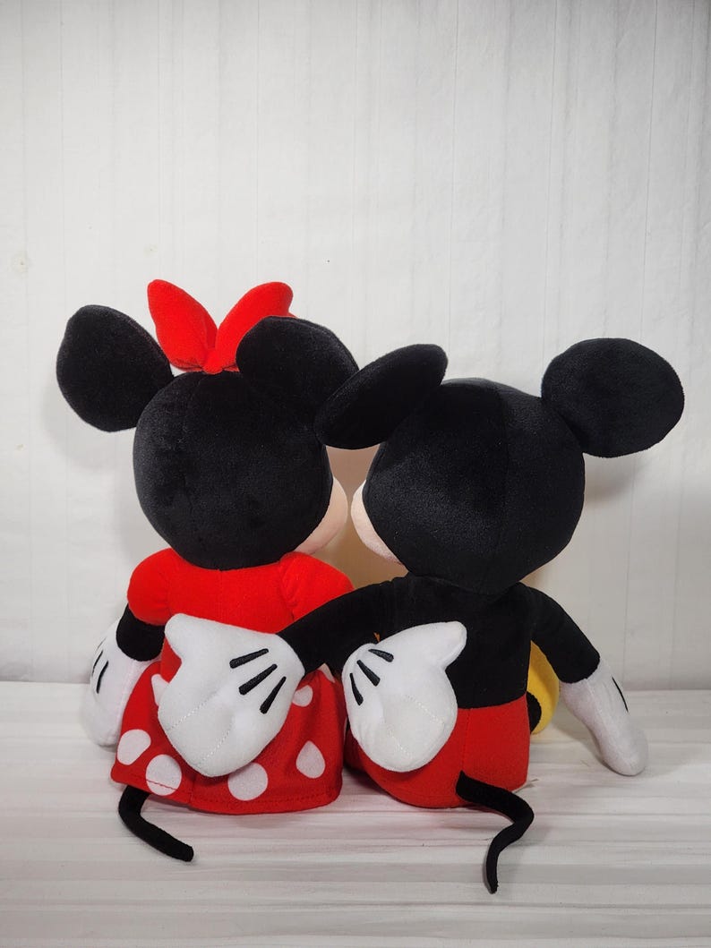 Pu&ograve; includere: Due peluche di Topolino e Minnie Mouse. Topolino indossa pantaloncini rossi, una giacca nera e guanti bianchi. Minnie indossa un vestito rosso a pois bianchi, un fiocco rosso e guanti bianchi. Entrambi hanno orecchie nere.