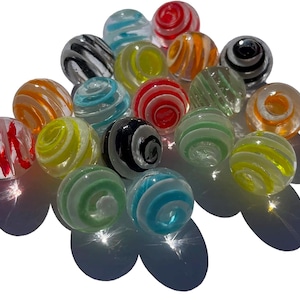 Op de afbeelding: Een verzameling kleurrijke glazen knikkers met verschillende patronen, waaronder swirls, strepen en stippen. De knikkers zijn willekeurig gerangschikt op een wit oppervlak.