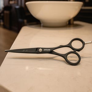Könnte beinhalten: Schwarze professionelle Haarscheren mit dem Markennamen "JAGUAR" auf der Klinge. Die Schere hat eine elegante, matte Oberfläche und ergonomische Fingerlöcher. Die Modellnummer "JP.10" ist auf der Klinge aufgedruckt. Die Schere ist für präzises Schneiden konzipiert.