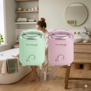 May include: Two electric hair removal wax warmers, one mint green and one pastel pink, are displayed. Each warmer has a clear lid, a temperature control dial, and the text "EPIL HAIR PRO" printed on the front. The warmers are on a wooden floor.