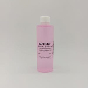 Op de afbeelding: Een doorzichtige fles met een witte dop, gevuld met roze vloeistof. Het etiket toont Duitse tekst, waaronder "STERN Mastix - Entferner" en een volume van 100 ml. De fles heeft ook een waarschuwingslabel. Het product is waarschijnlijk een oplosmiddel of lijmverwijderaar.