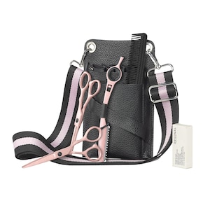 Könnte beinhalten: Schwarze Friseur-Werkzeugtasche aus Leder mit rosa-schwarzem Streifenriemen. Enthält rosa Scheren, einen Rasierer und einen Kamm. Eine kleine weiße Box mit Text befindet sich auf der rechten Seite. Für professionelle Friseure.