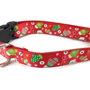 May include: Red dog collar with a Christmas mitten pattern. The collar has a black plastic buckle and a silver D-ring.
