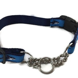 May include: Navy blue dog collar with a shark pattern on light blue accents. The collar features a black plastic buckle and a silver metal chain for leash attachment. A stylish accessory for your pet.