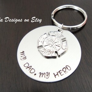May include: Silver keychain with a round tag that says "My Dad. My Hero." and a silver firefighter emblem charm.