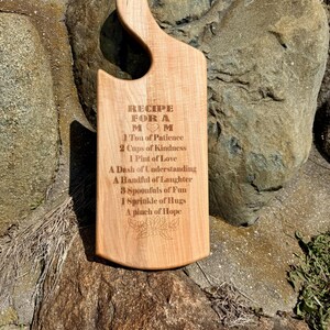May include: A wooden chopping board with a recipe for a mum engraved on it. The recipe includes ingredients such as patience, kindness, love, understanding, laughter, fun, hugs, and hope.