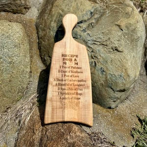 May include: A wooden chopping board with a recipe for a mum engraved on it. The recipe includes ingredients such as patience, kindness, love, understanding, laughter, fun, hugs, and hope.