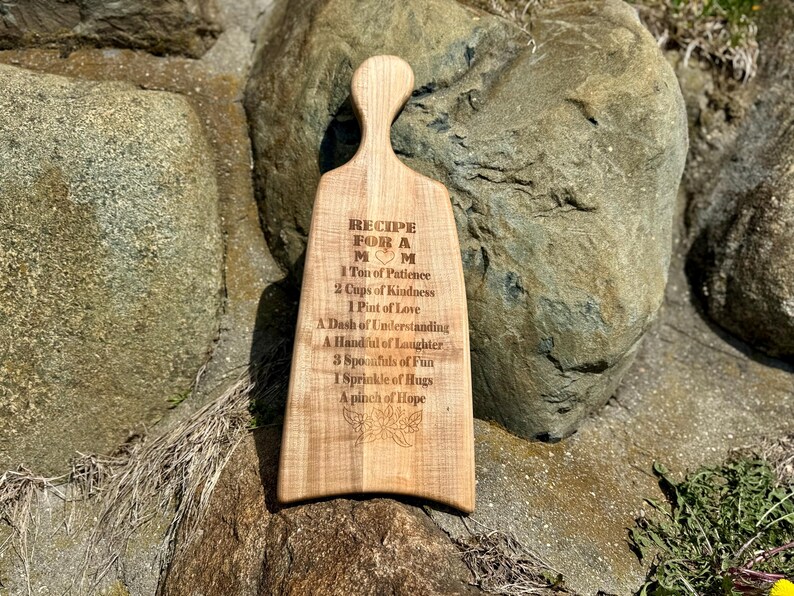 May include: A wooden chopping board with a recipe for a mum engraved on it. The recipe includes ingredients such as patience, kindness, love, understanding, laughter, fun, hugs, and hope.