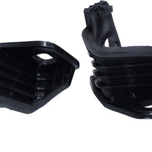May include: Two black plastic automotive parts, likely a set, are displayed against a white background. Each part has a unique shape with a series of horizontal ridges and a protruding section. The parts appear to be new and unused.