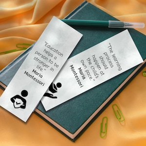 May include: Two white bookmarks with black text and illustrations. The text on the bookmarks reads "Education helps a person to be stronger in life." and "The learning process should happen at the child's own pace." Both bookmarks include the name Maria Montessori.